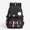 Vue de face du sac à dos collège noir avec pompon blanc et motif à carreaux rose