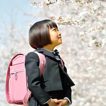 petite fille portant un sac à dos scolaire japonais randoseru sous les cerisiers en fleurs