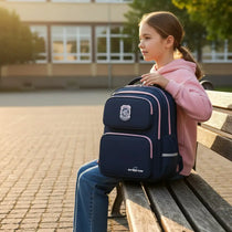 Sac à dos ergonomique bleu marine porté par une fille assise devant son école