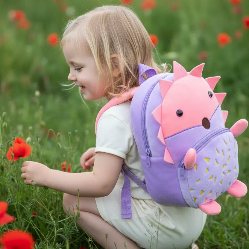 Sac à dos maternelle en peluche hérisson rose et violet porté par une petite fille en extérieur