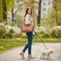 Femme marchant avec un sac cabas en cuir camel, tenue claire et ambiance de promenade printanière.