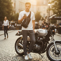 Homme portant un sac de poitrine noir en milieu urbain, près d’une moto