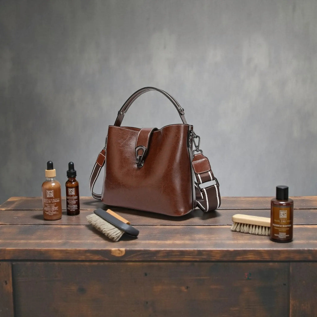 Sac à main en cuir véritable brun posé sur une table avec accessoires d’entretien du cuir, illustrant la durabilité et le soin des sacs en cuir haut de gamme.