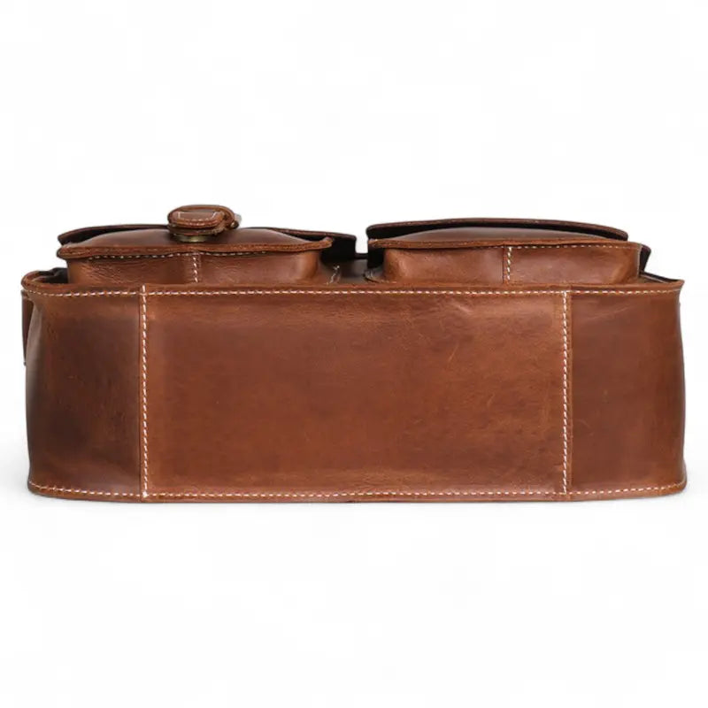 Vue du dessous d’un cartable en cuir marron, base renforcée avec coutures visibles.