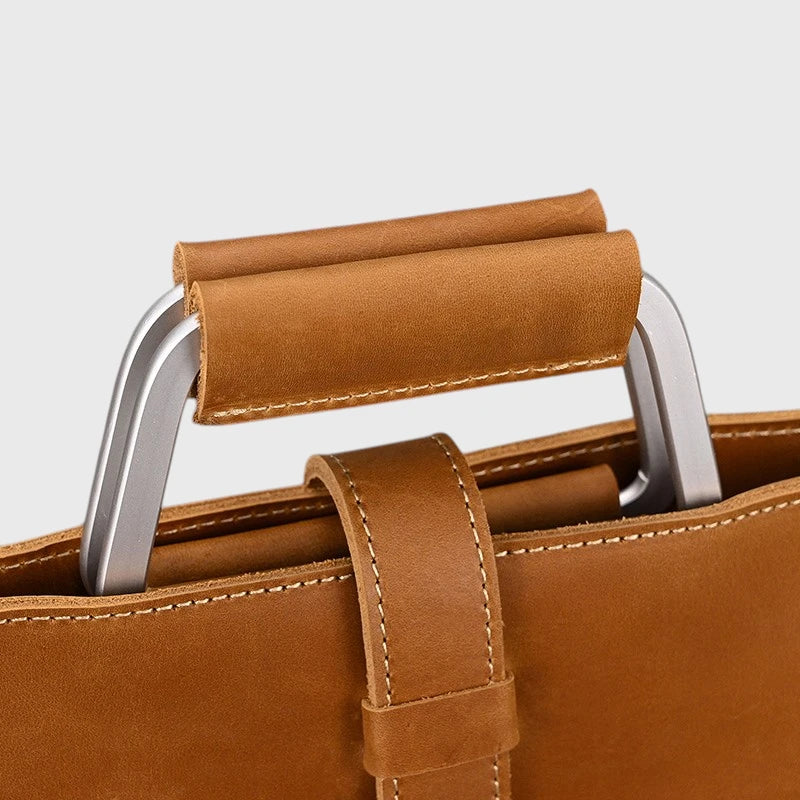 Gros plan sur la poignée renforcée du porte-documents en cuir marron avec finition en cuir véritable