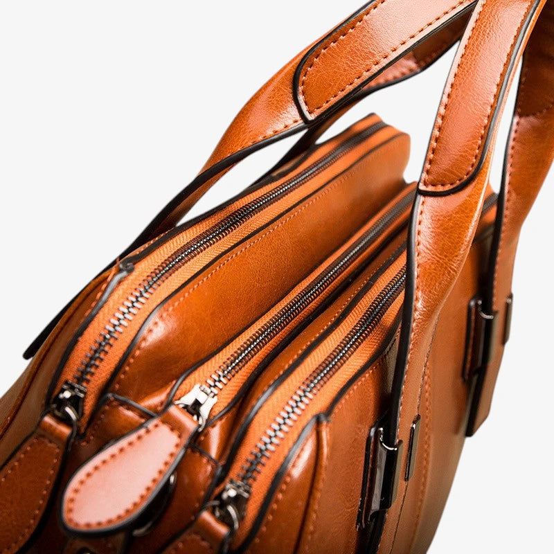 Détail des fermetures zippées et des tirettes du sac en cuir marron