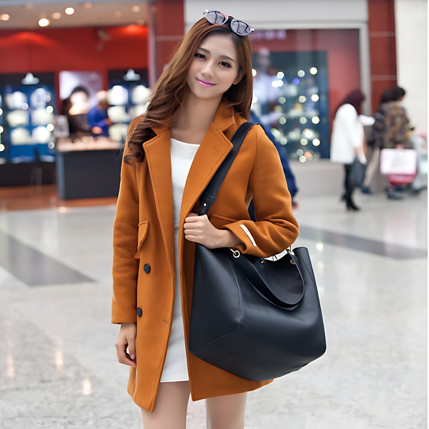 Femme en manteau orange portant un sac cabas noir à l’épaule