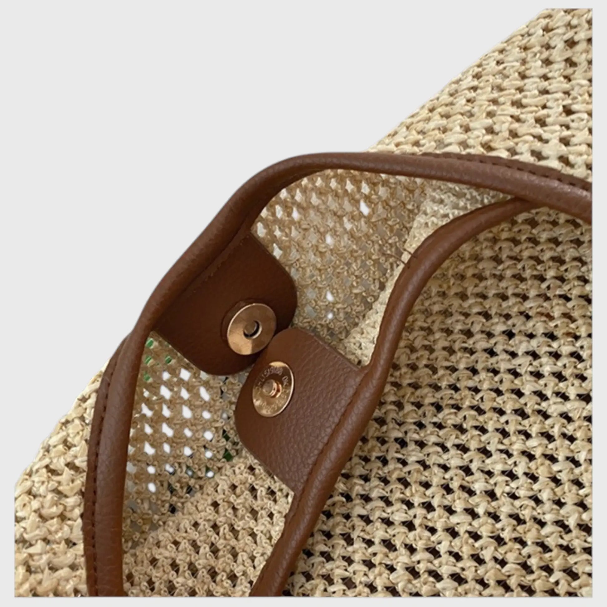 Détail de la fermeture pression du sac cabas en paille beige avec finition marron