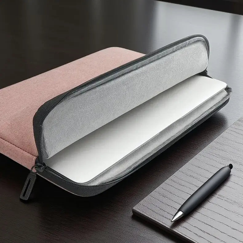 Housse ordinateur portable grise posée sur bureau avec clavier et accessoires