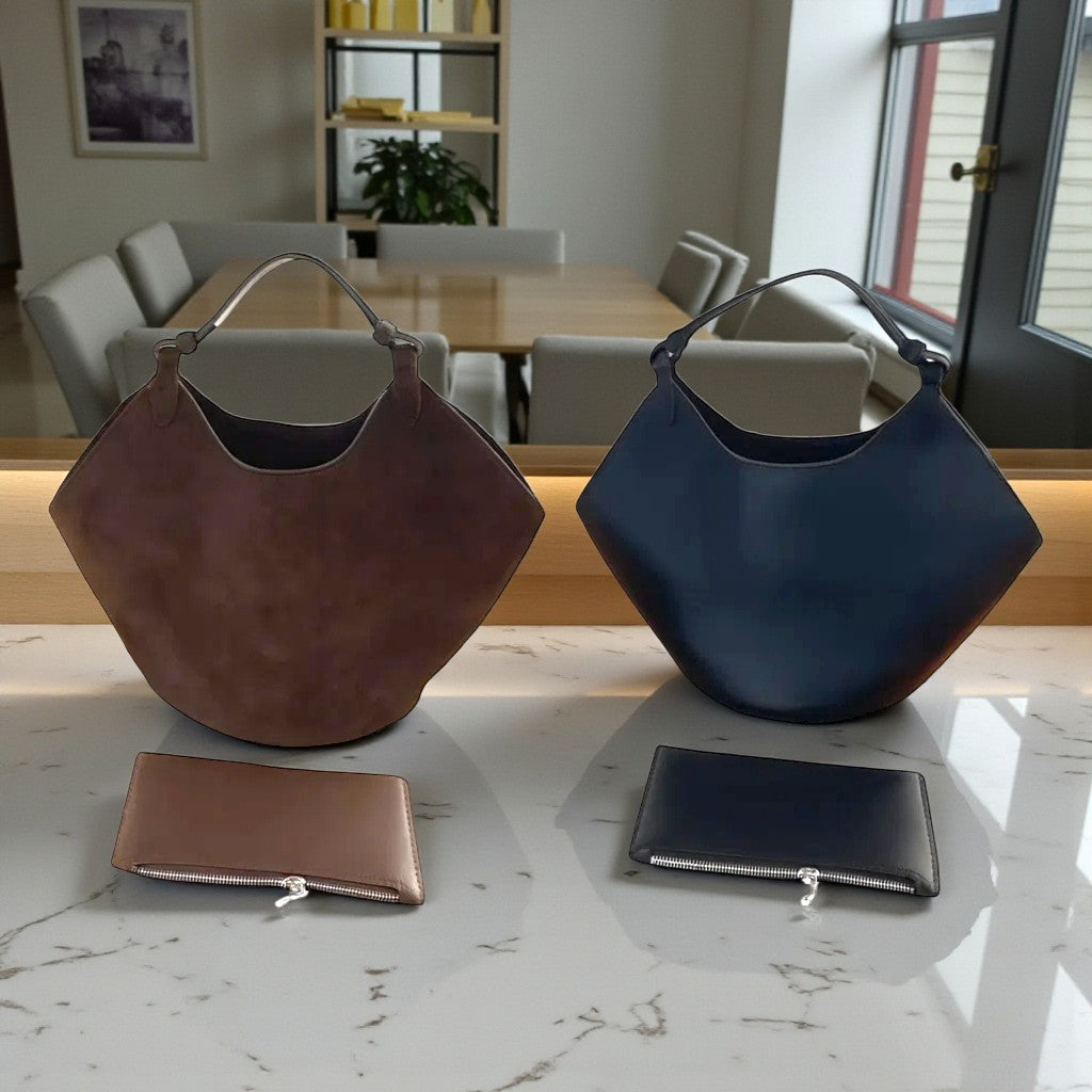 Présentation du petit sac seau en cuir noir et du petit sac seau en cuir suédé marron posés sur une table