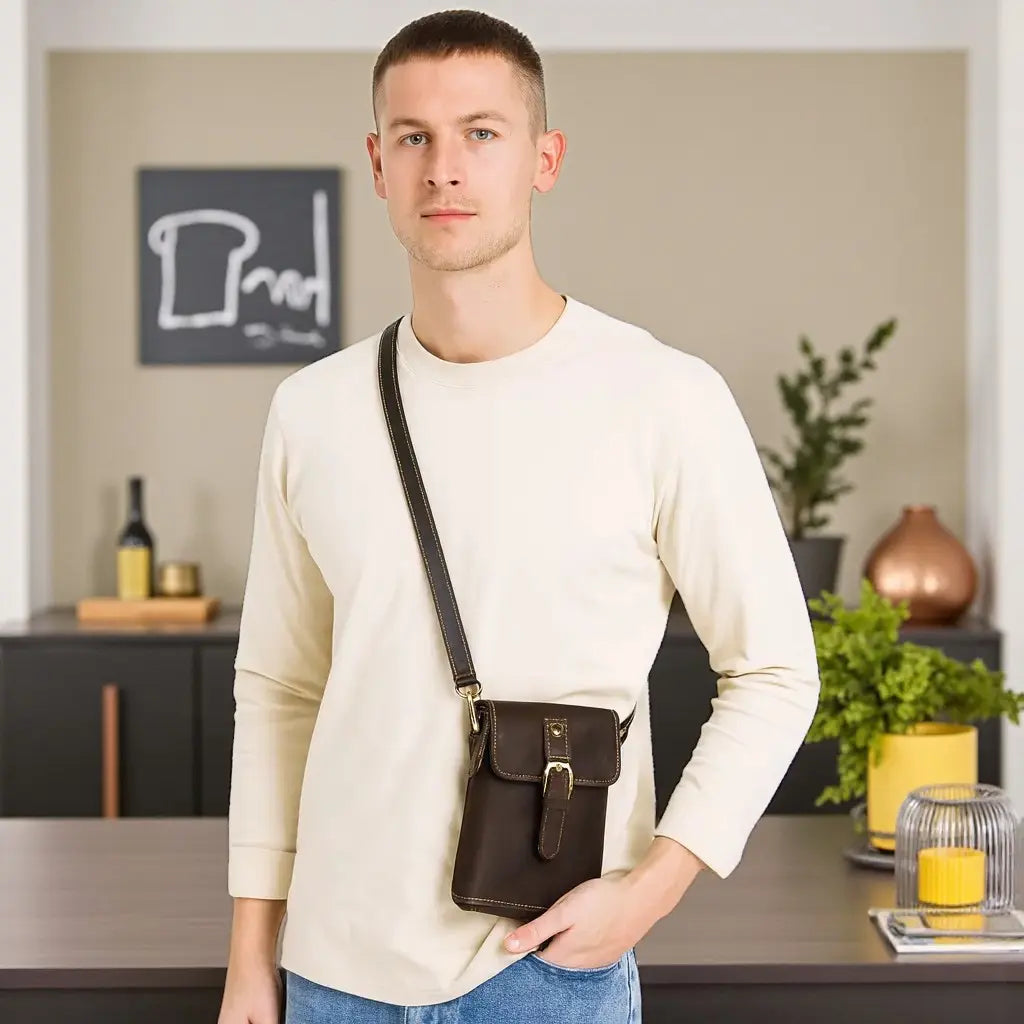 Jeune homme  portant une pochette à bandoulière en cuir vintage marron sur fond blanc avec tenue beige décontractée