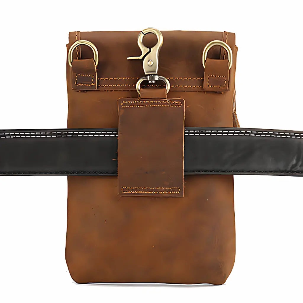 Pochette en cuir marron portée à la ceinture grâce à son mousqueton