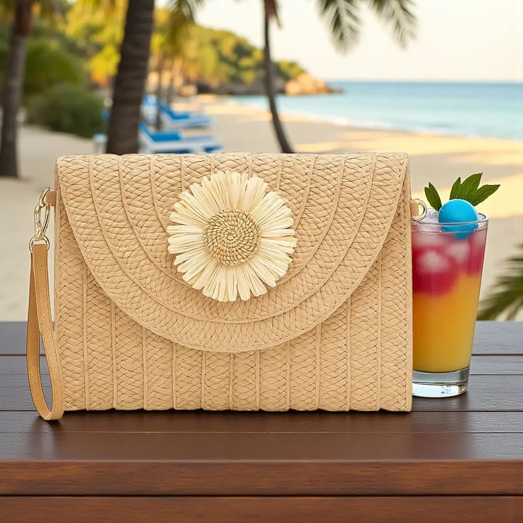 Pochette en paille tressée beige posée sur une table avec vue sur la plage
