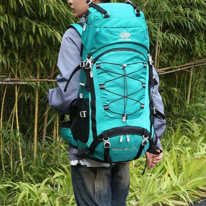 Sac à dos trekking 60L turquoise porté en extérieur – vue sur le dos d’un homme en tenue de randonnée