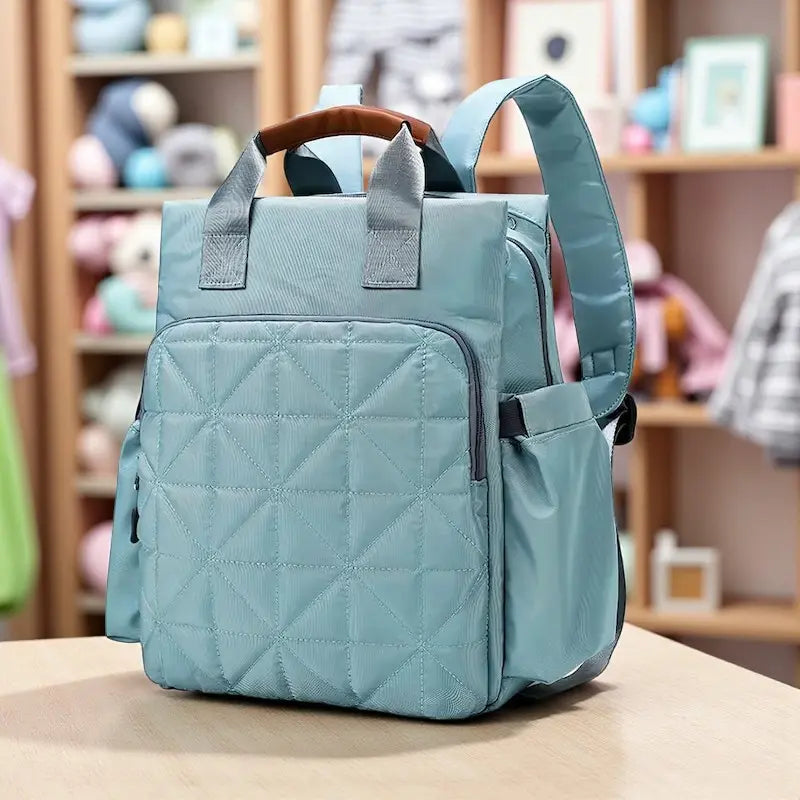 Sac à dos à langer bleu clair posé sur une table en bois.