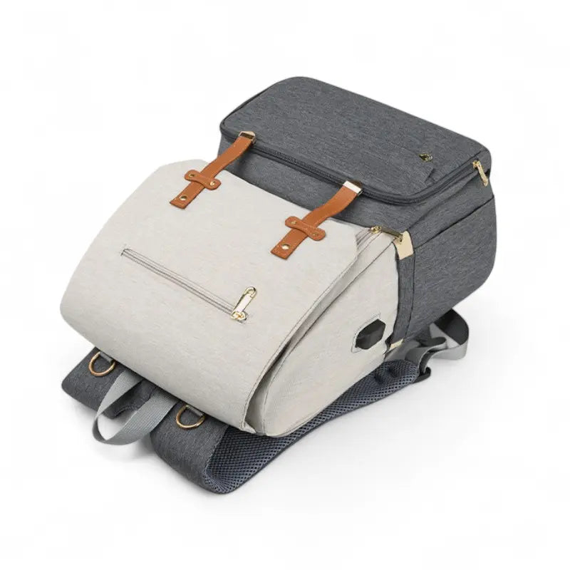 Vue de face du sac à dos à langer gris et beige avec attaches en cuir marron