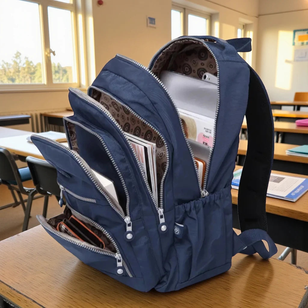Sac à dos scolaire bleu marine ouvert avec livres et cahiers en salle de classe