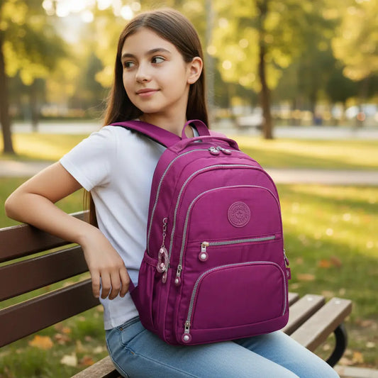 Sac à dos collège fille fuchsia porté assise sur un banc en extérieur