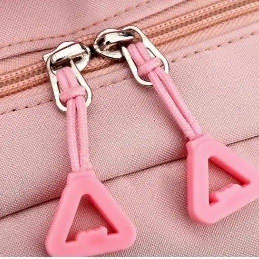 Zoom sur les fermetures éclair roses en forme de triangle du sac à dos collège