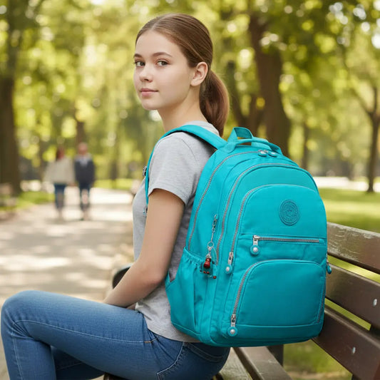 Sac à dos scolaire fille turquoise porté assise sur un banc en extérieur