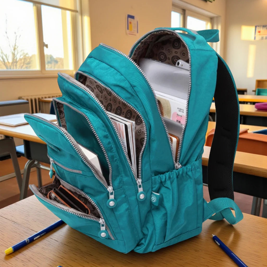 Sac à dos scolaire fille turquoise ouvert avec livres et cahiers en salle de classe
