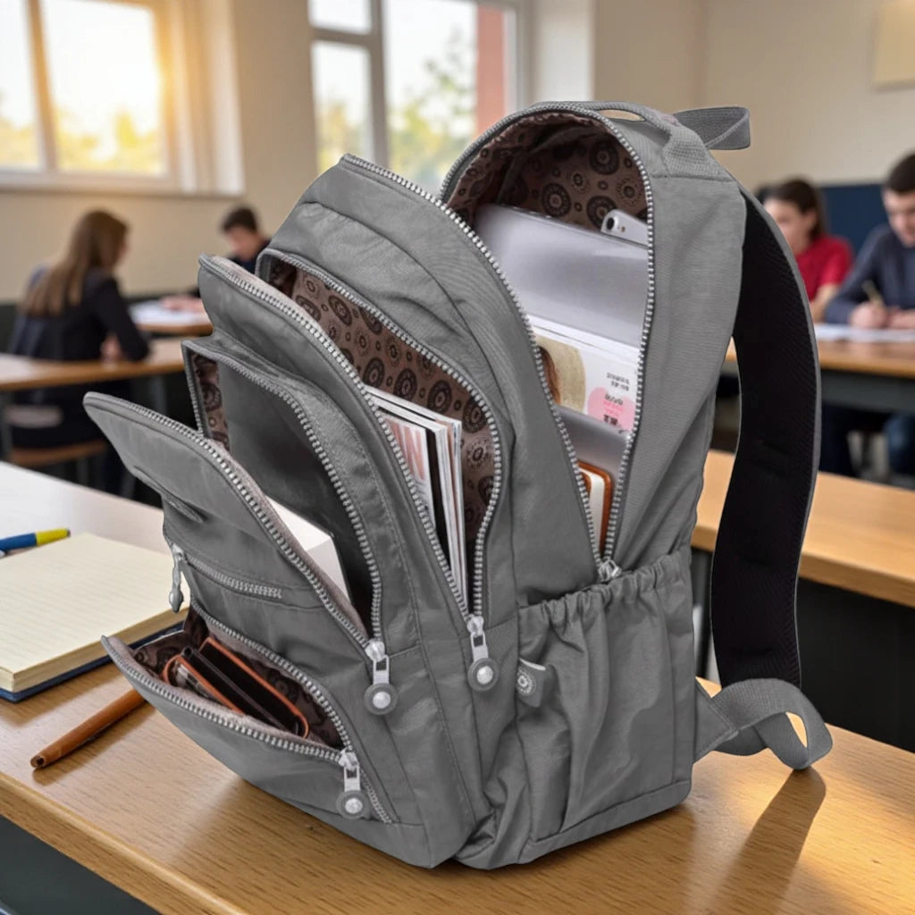 Sac à dos scolaire garçon gris ouvert avec livres et cahiers en salle de classe