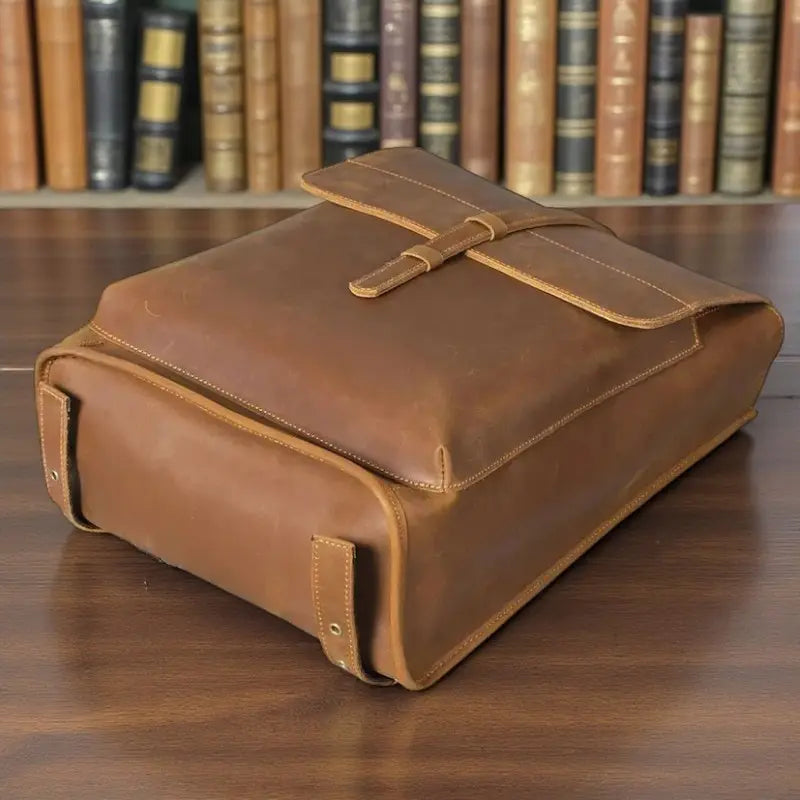 Vue du dessous du sac à dos en cuir véritable de vachette marron avec rabat et boucle