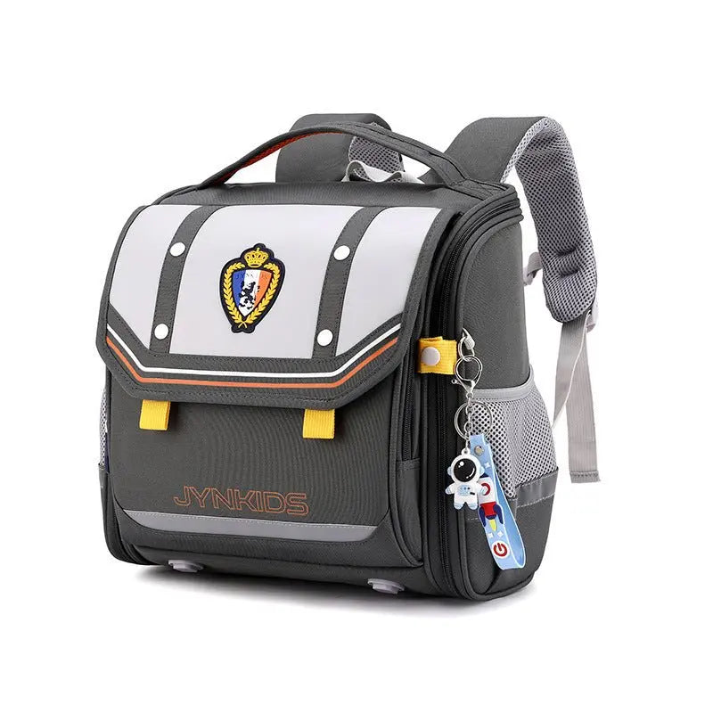 Sac à dos scolaire gris et blanc JYNKIDS avec écusson doré, accents orange et porte-clés fusée – modèle enfant primaire
