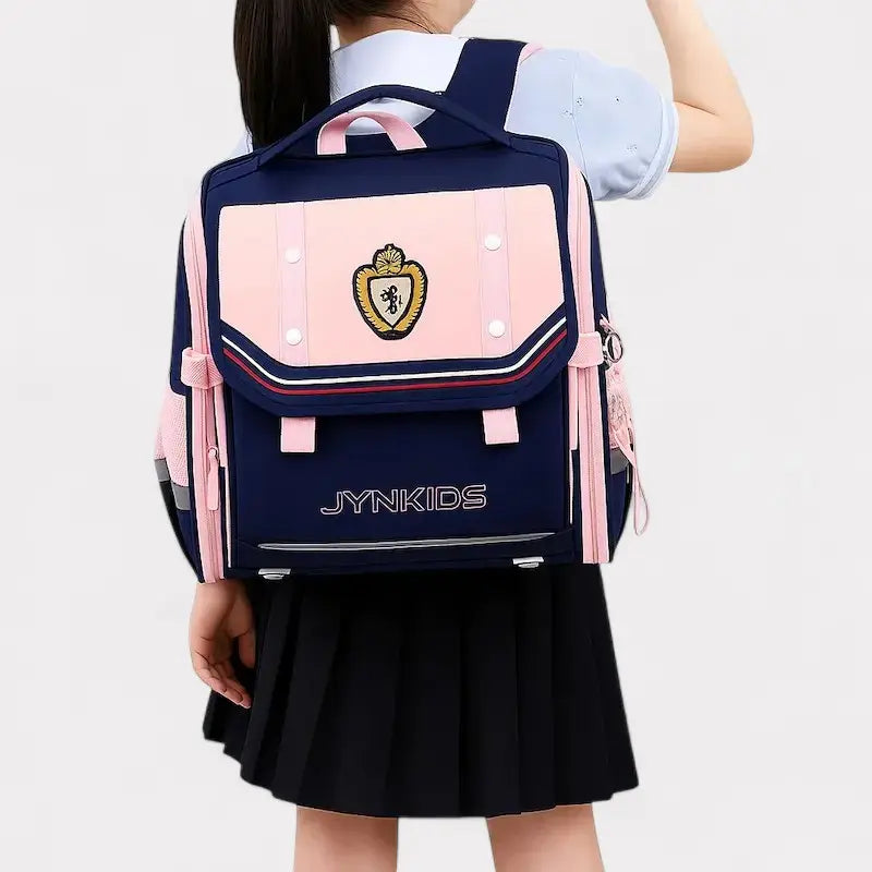 Sac à dos scolaire rose et bleu style britannique avec écusson doré et porte-clés – porté par une écolière en tenue uniforme
