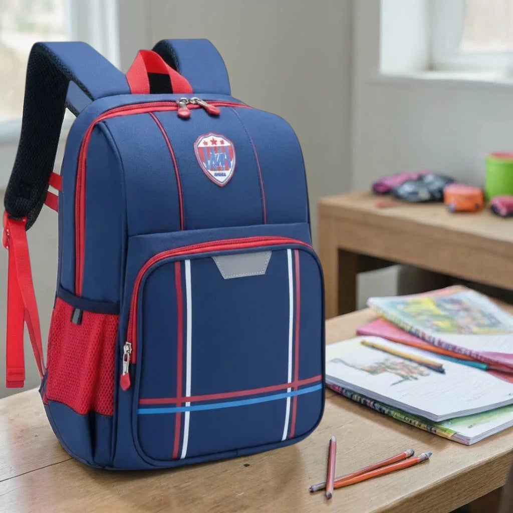 Sac à dos ergonomique bleu et rouge posé sur un bureau avec cahiers et fournitures scolaires
