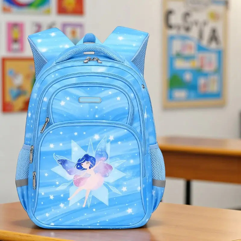 Sac à dos ergonomique bleu avec motif de fée posé sur un bureau d’école.