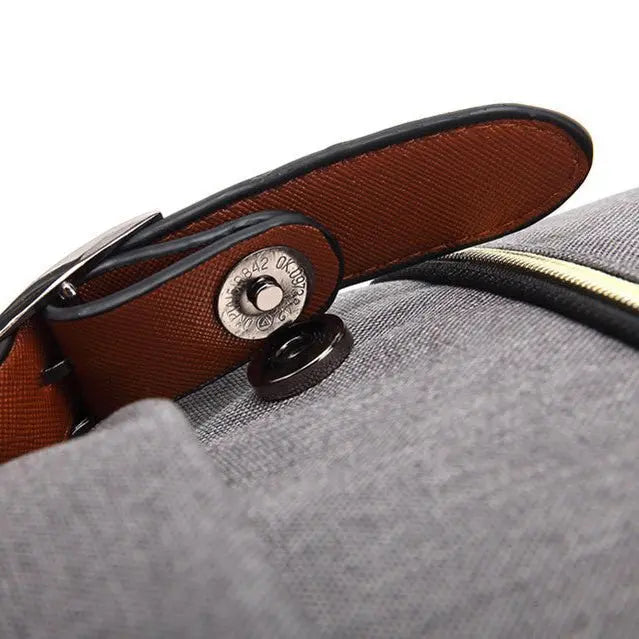 Zoom sur le rabat avec fermeture magnétique du sac à dos gris et empiècement marron