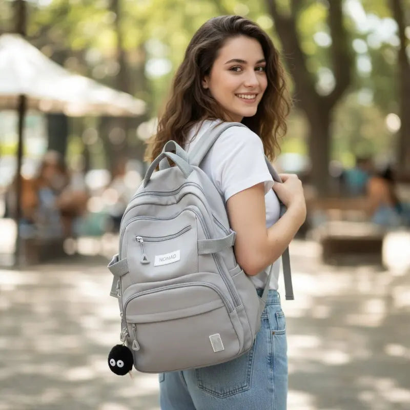 Étudiante en extérieur avec un sac à dos gris spacieux et fonctionnel.