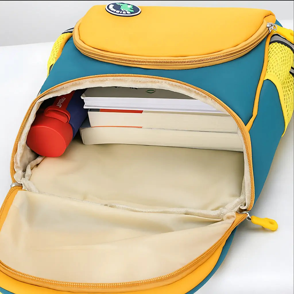 Intérieur du sac à dos maternelle dinosaure jaune avec tablette et cahiers rangés.