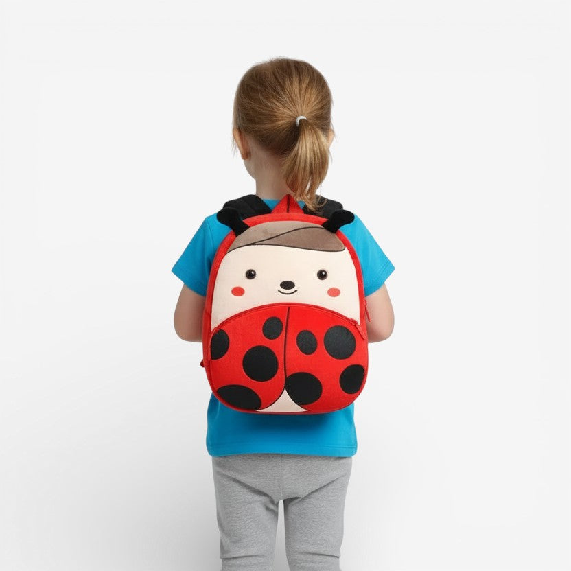 Sac à dos maternelle en peluche coccinelle porté par un enfant
