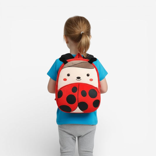 Sac à dos maternelle en peluche coccinelle porté par un enfant

