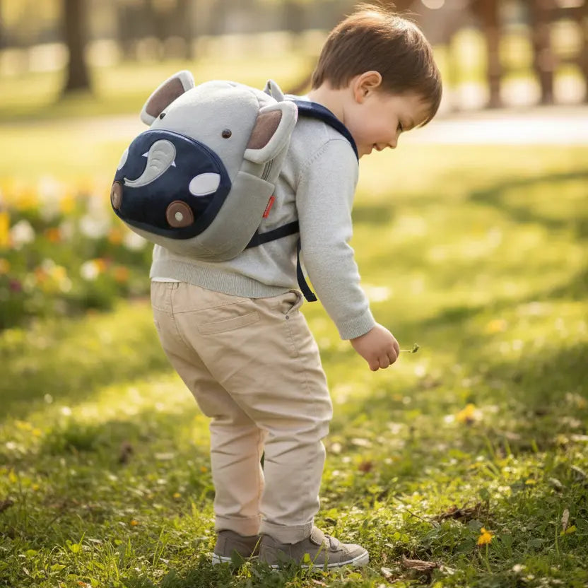 Sac à dos maternelle en peluche éléphant porté par un enfant en extérieur
