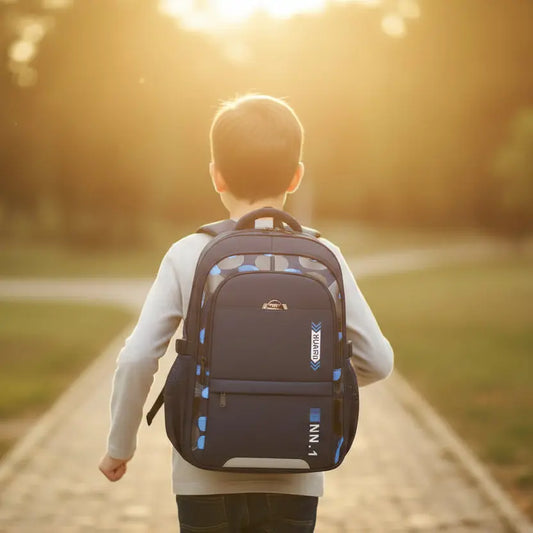 Garçon portant un sac à dos scolaire ergonomique bleu marine de dos en extérieur