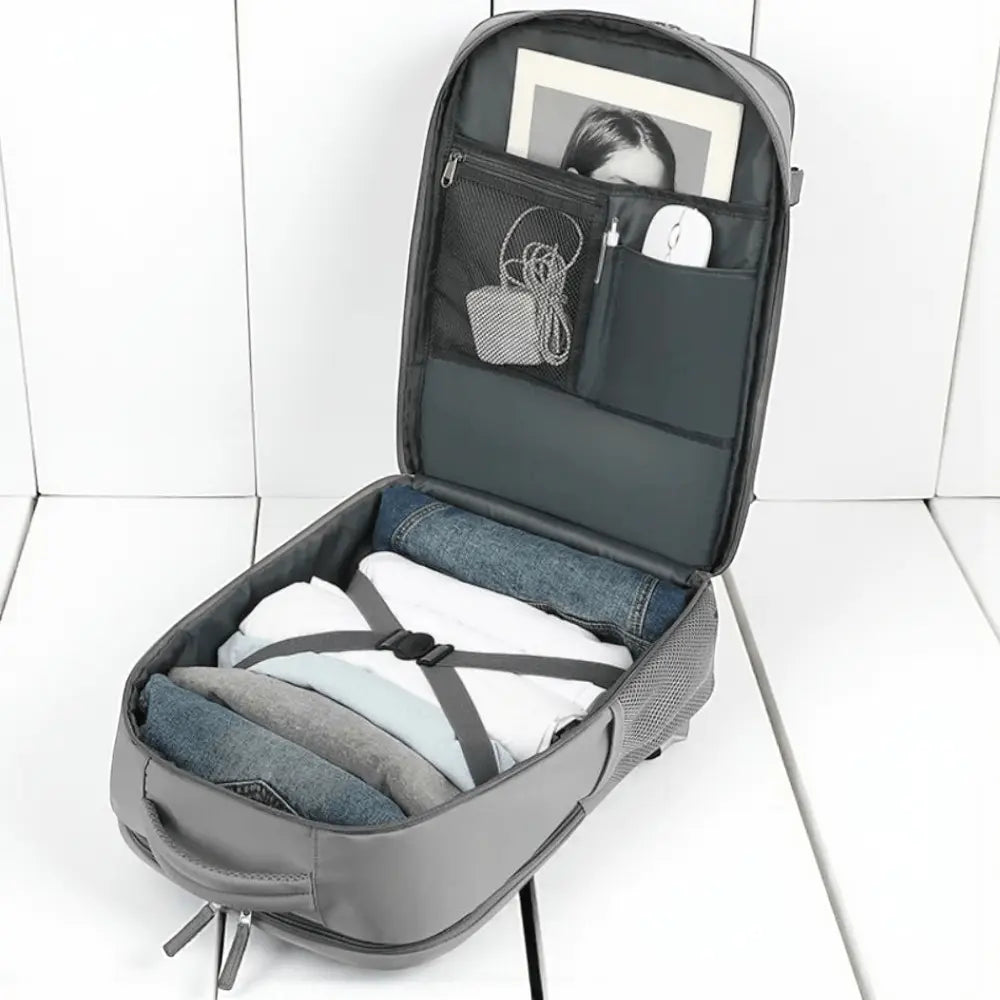 Sac à dos de voyage mixte gris ouvert montrant ses compartiments intérieurs pour vêtements, accessoires et ordinateur portable