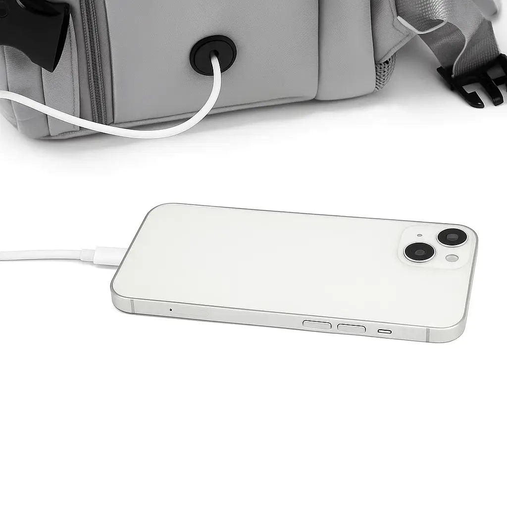 Détail du port USB intégré sur le sac à dos de voyage mixte gris avec câble de chargement connecté à un smartphone