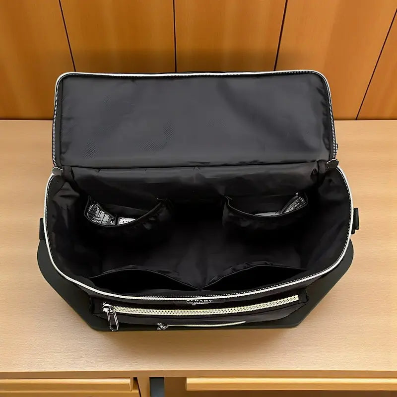 Sac à langer bandoulière noir ouvert montrant les compartiments intérieurs