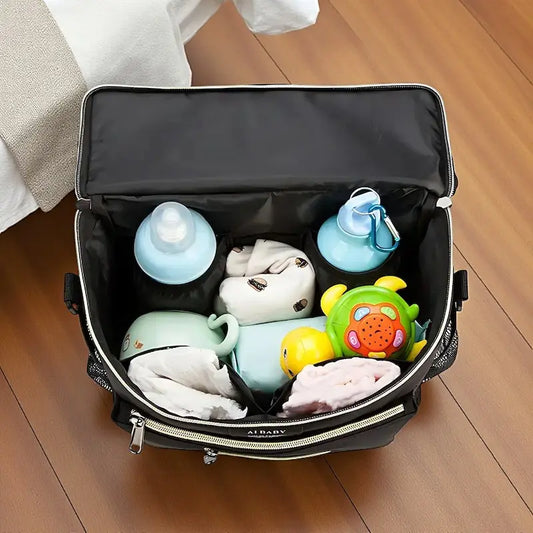 Sac à langer bandoulière noir ouvert avec biberons et jouets rangés