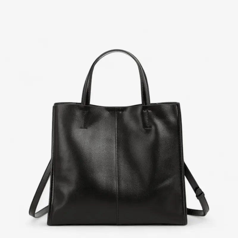 Vue de face d’un sac à main noir en cuir souple avec double poignée et bandoulière.