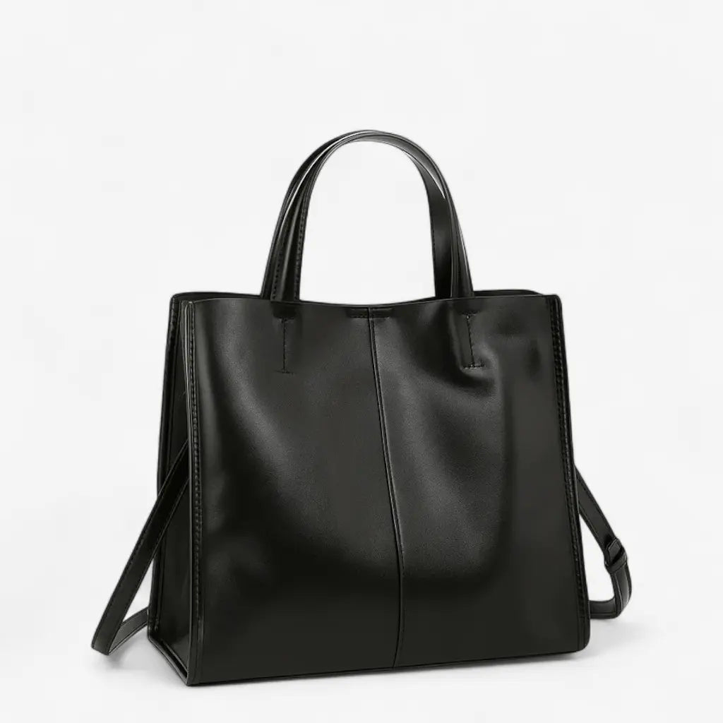 Sac à main noir en cuir de vachette, structure carrée avec double anse et bandoulière amovible.