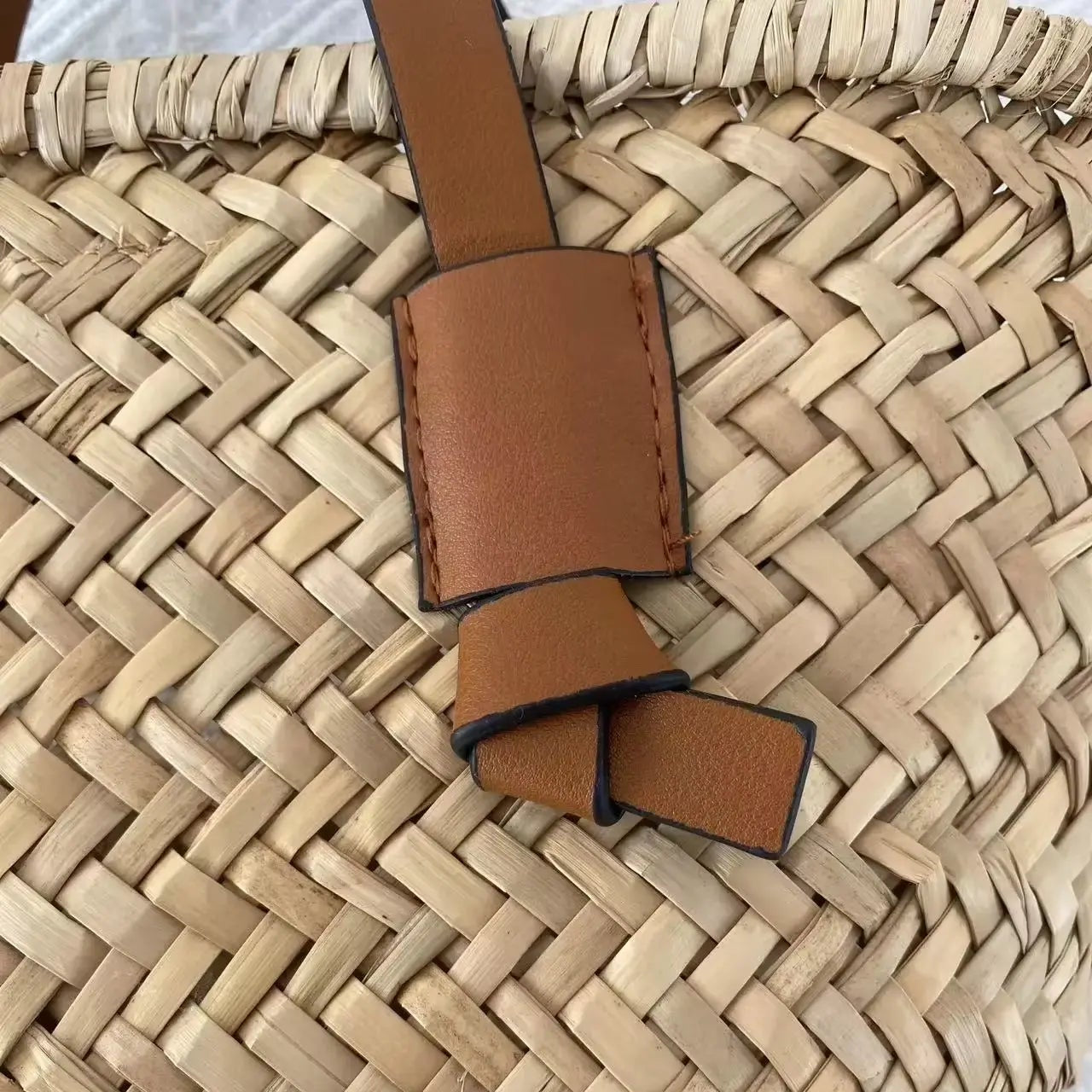 Détail de la fixation en similicuir marron sur sac à main bohème en paille tressée