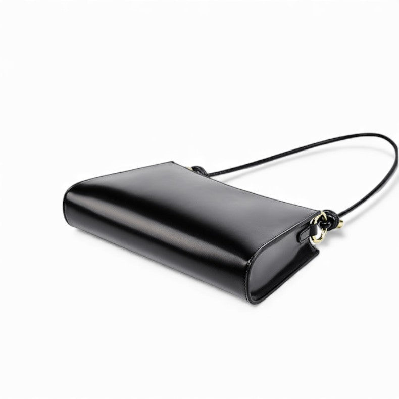 Sac baguette en cuir noir vu de dos posé sur surface blanche
