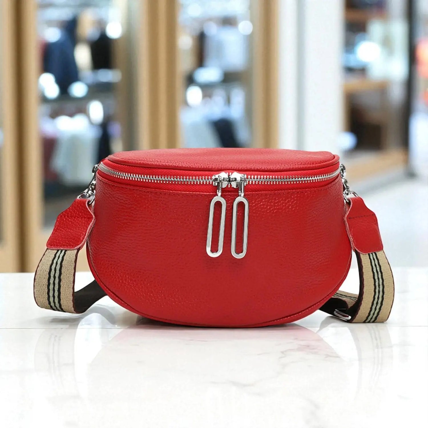 Sac banane femme en cuir véritable rouge avec fermeture zip double présenté en boutique.