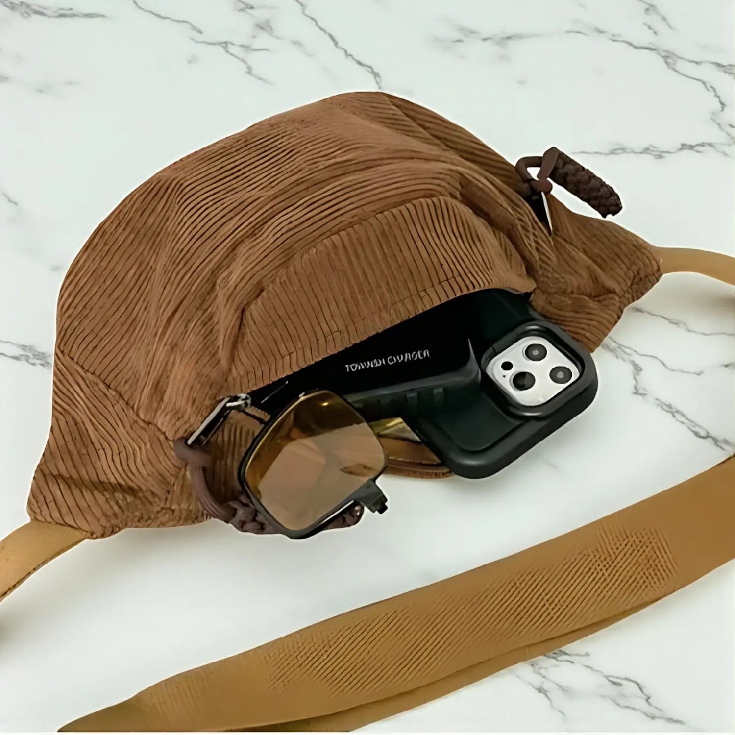 Intérieur d’un sac banane en velours côtelé marron avec accessoires rangés