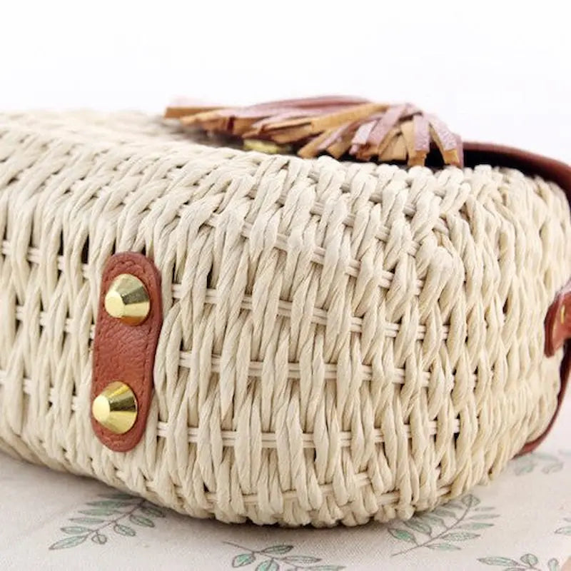 Détails du fond d’un sac bohème en paille tressée avec rivets métalliques dorés