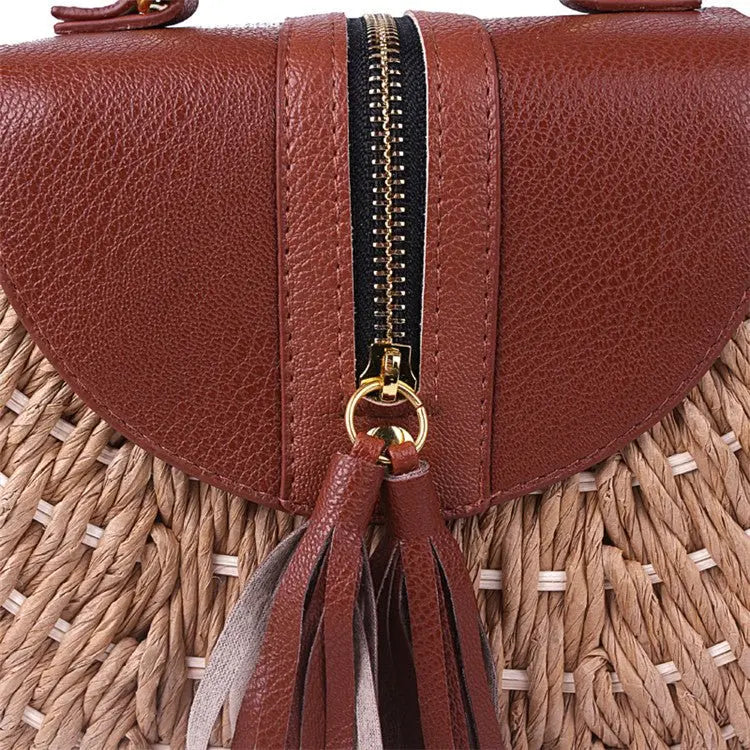 Zoom sur la fermeture éclair dorée d’un sac bohème en paille tressée avec rabat en cuir marron